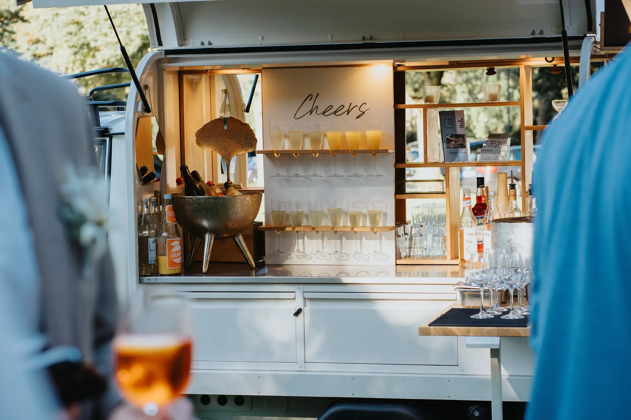Mobile Cocktailbar mit „Cheers“-Schild beim Hochzeits-Sektempfang