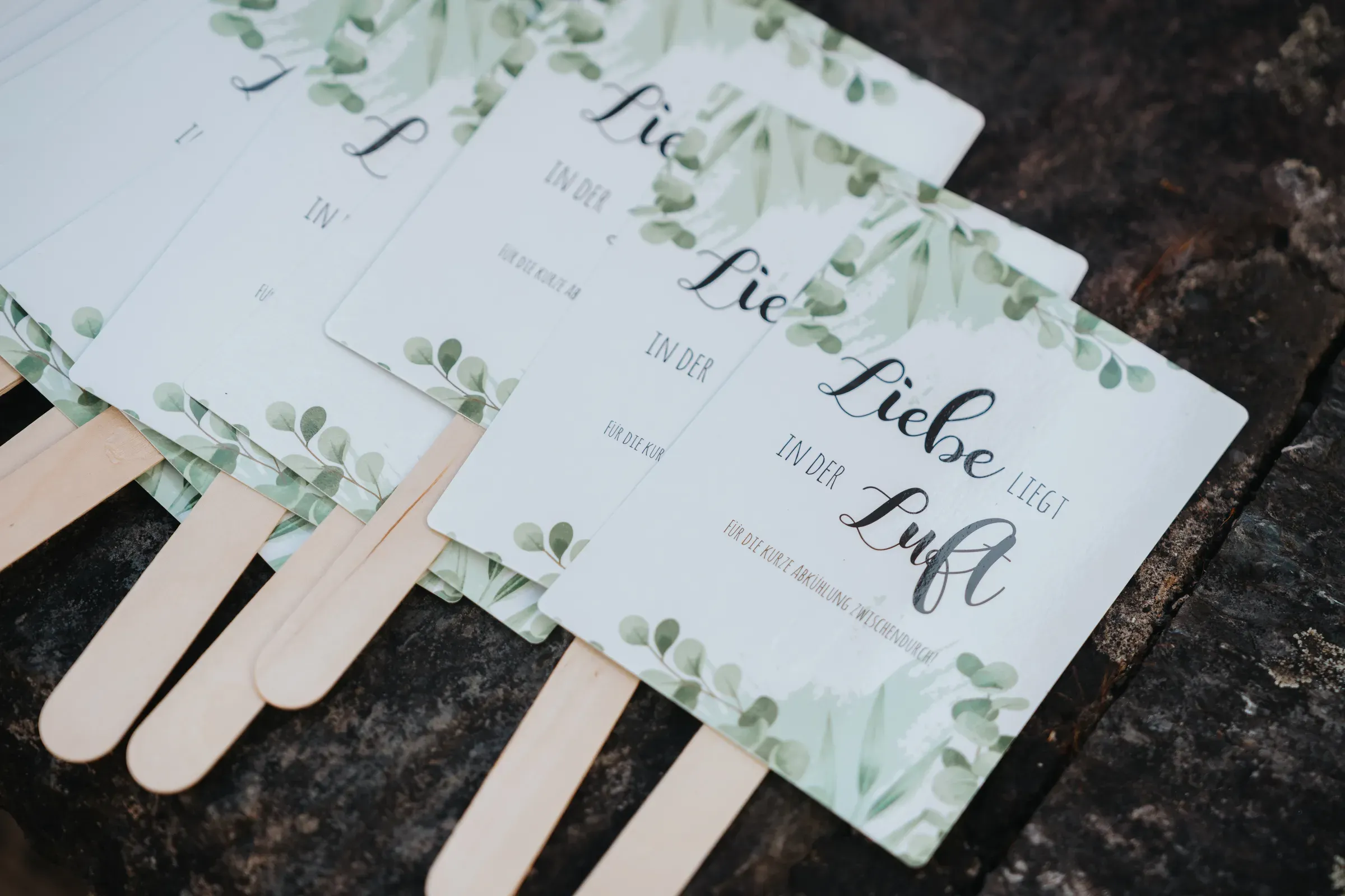 Papierfächer mit „Liebe liegt in der Luft“ als Gastgeschenk auf einer Hochzeit