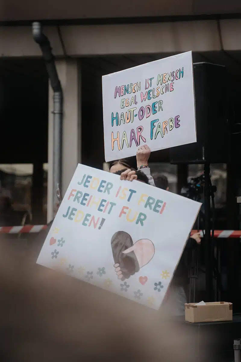 Zwei Schilder werden bei einer Demonstration hochgehalten.