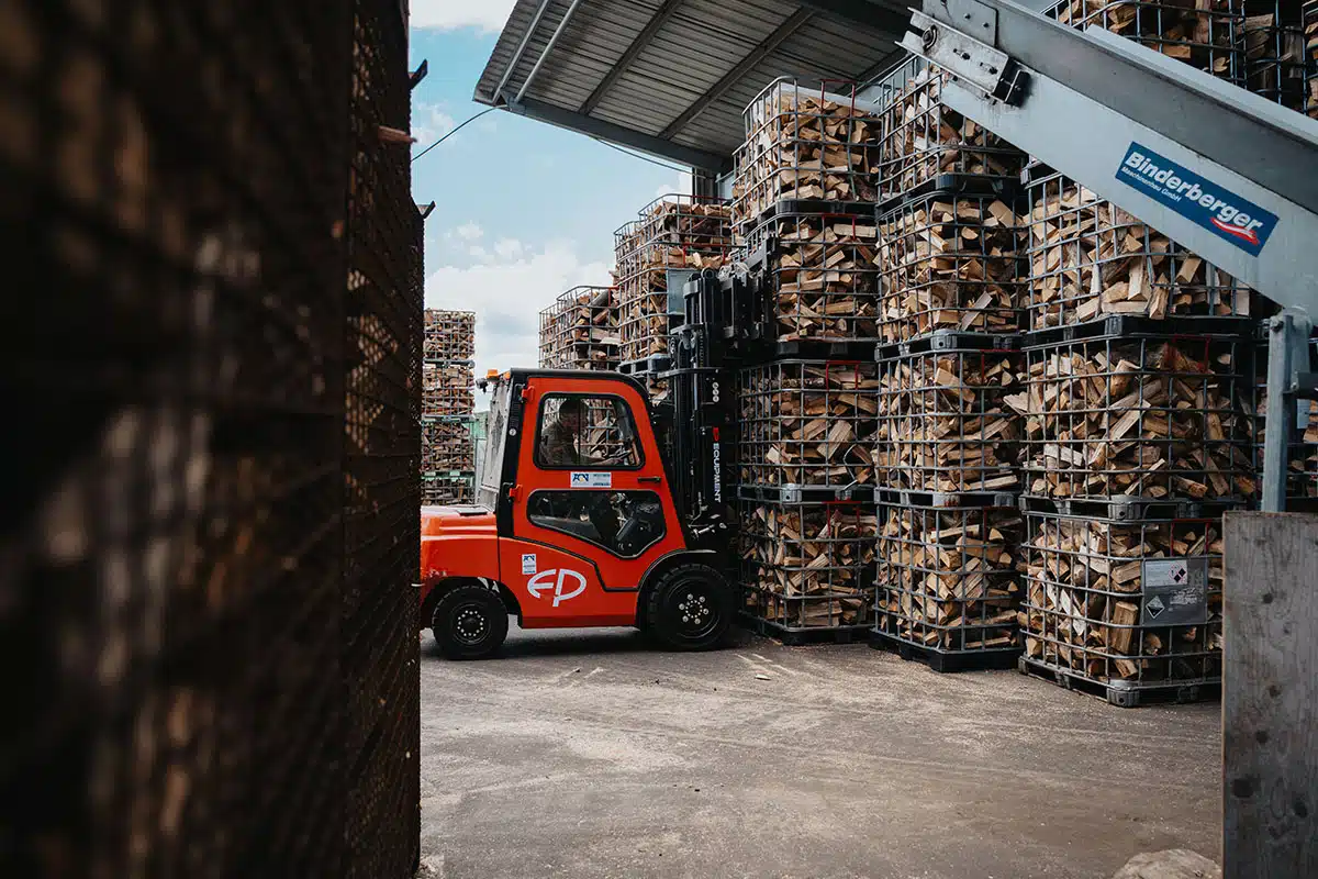 Ein Gabelstapler vor Boxen voll mit Holz.