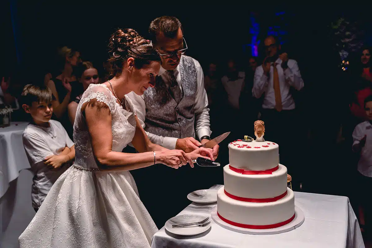 Braut und Bräutigam schneiden die Hochzeitstorte an.