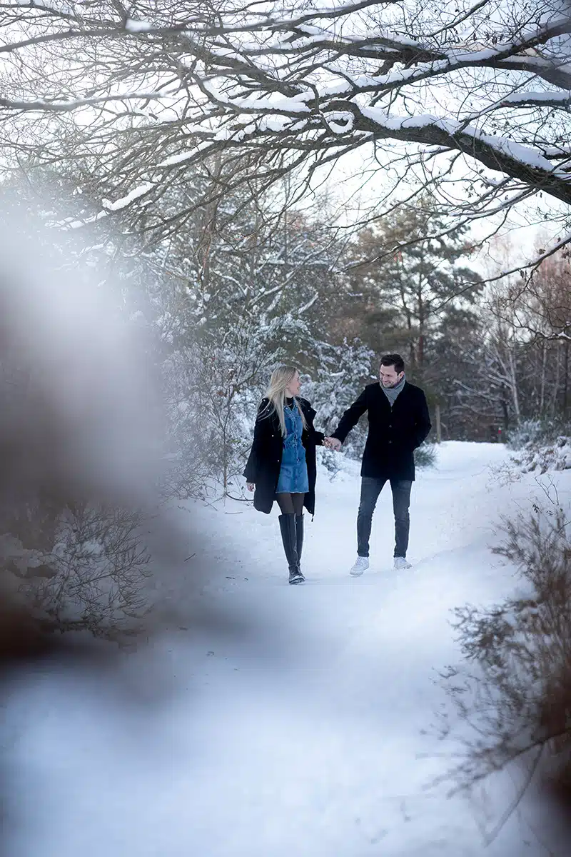 Ein paar läuft Hand in Hand durch eine winterliche Landschaft in der Wahner Heide.