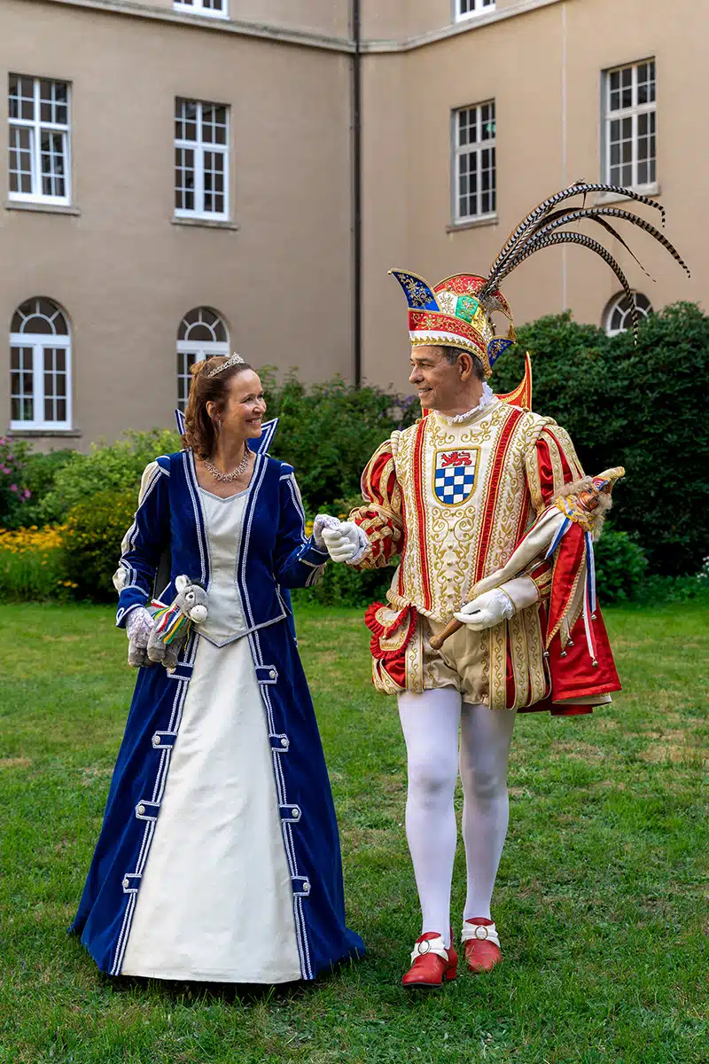 Das Sankt Augustiner Prinzenpaar 2023/2024 läuft Hand in Hand auf einer Wiese.