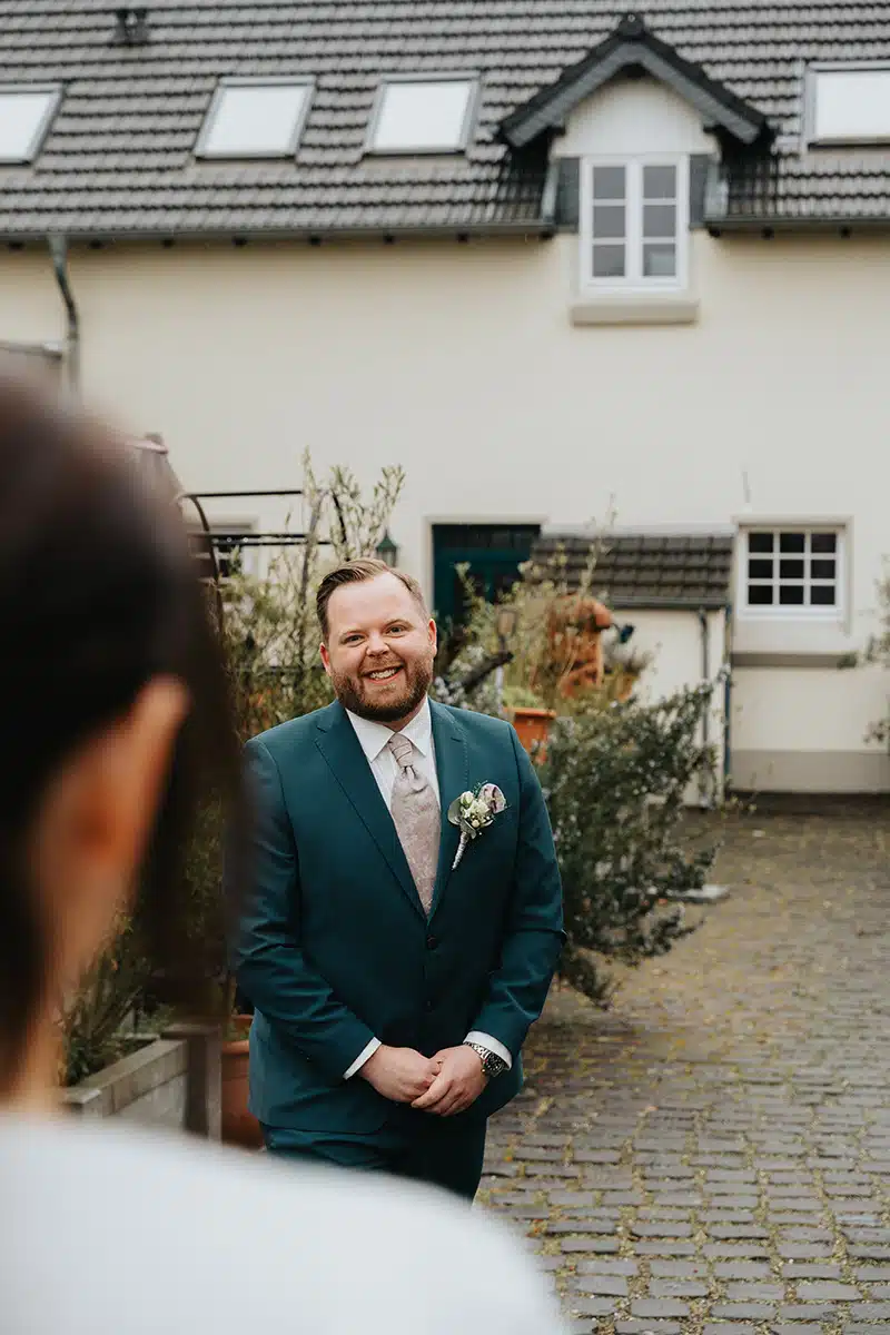Der Bräutigam dreht sich lächelnd beim First Look Shooting um.