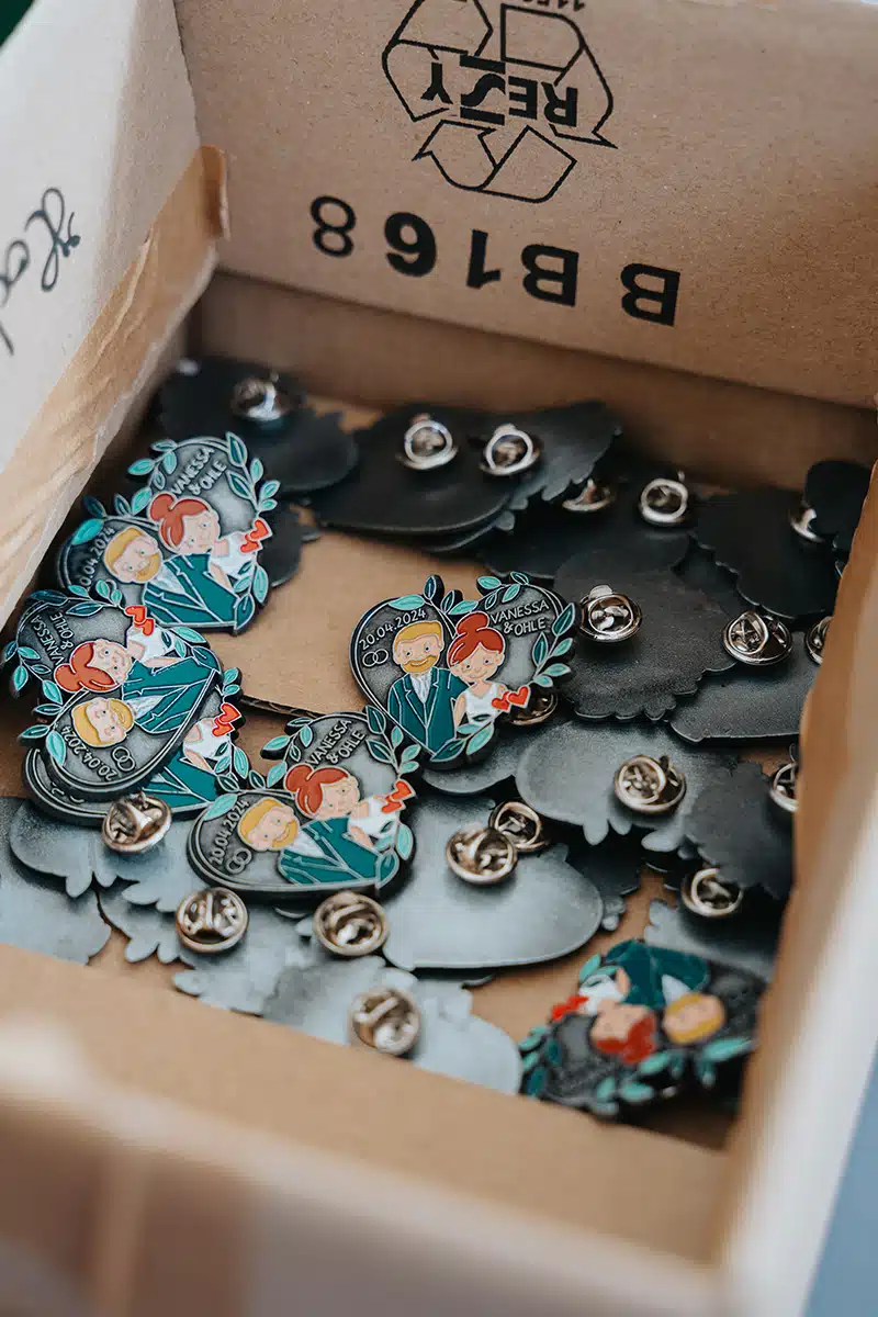 Kleine Blechpins mit den Abbildern des Brautpaares.