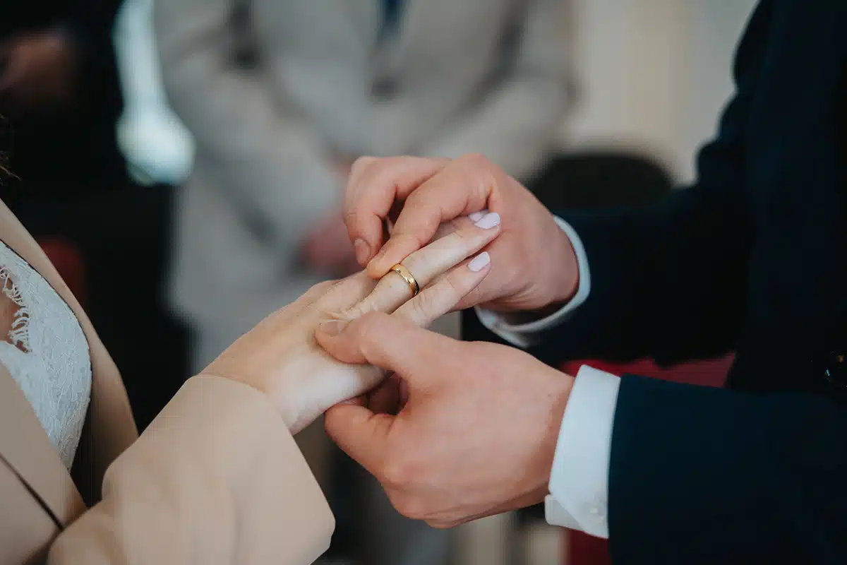 Bräutigam steckt der Braut einen Ring an den Finger.