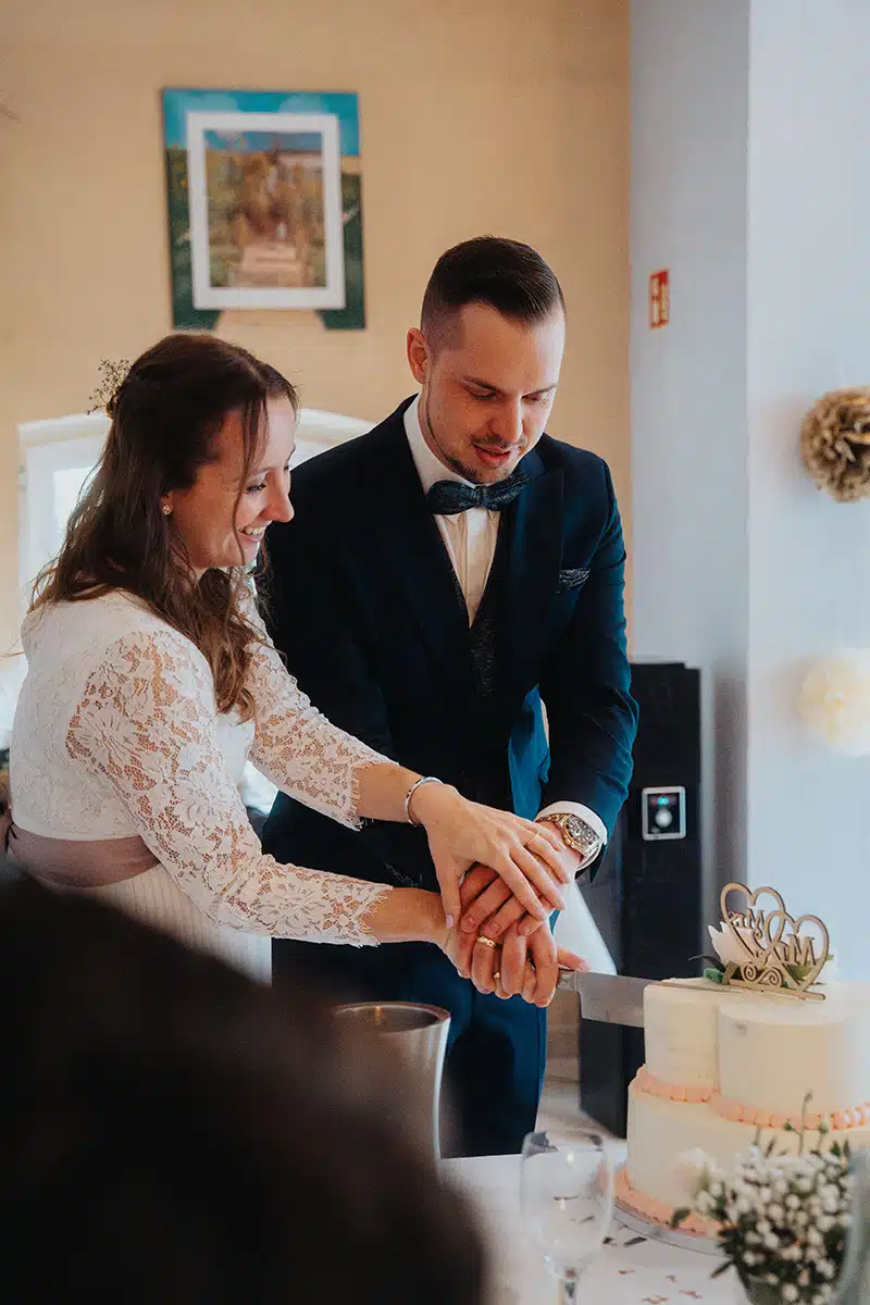 Braut und Bräutigam schneiden die Hochzeitstorte an.