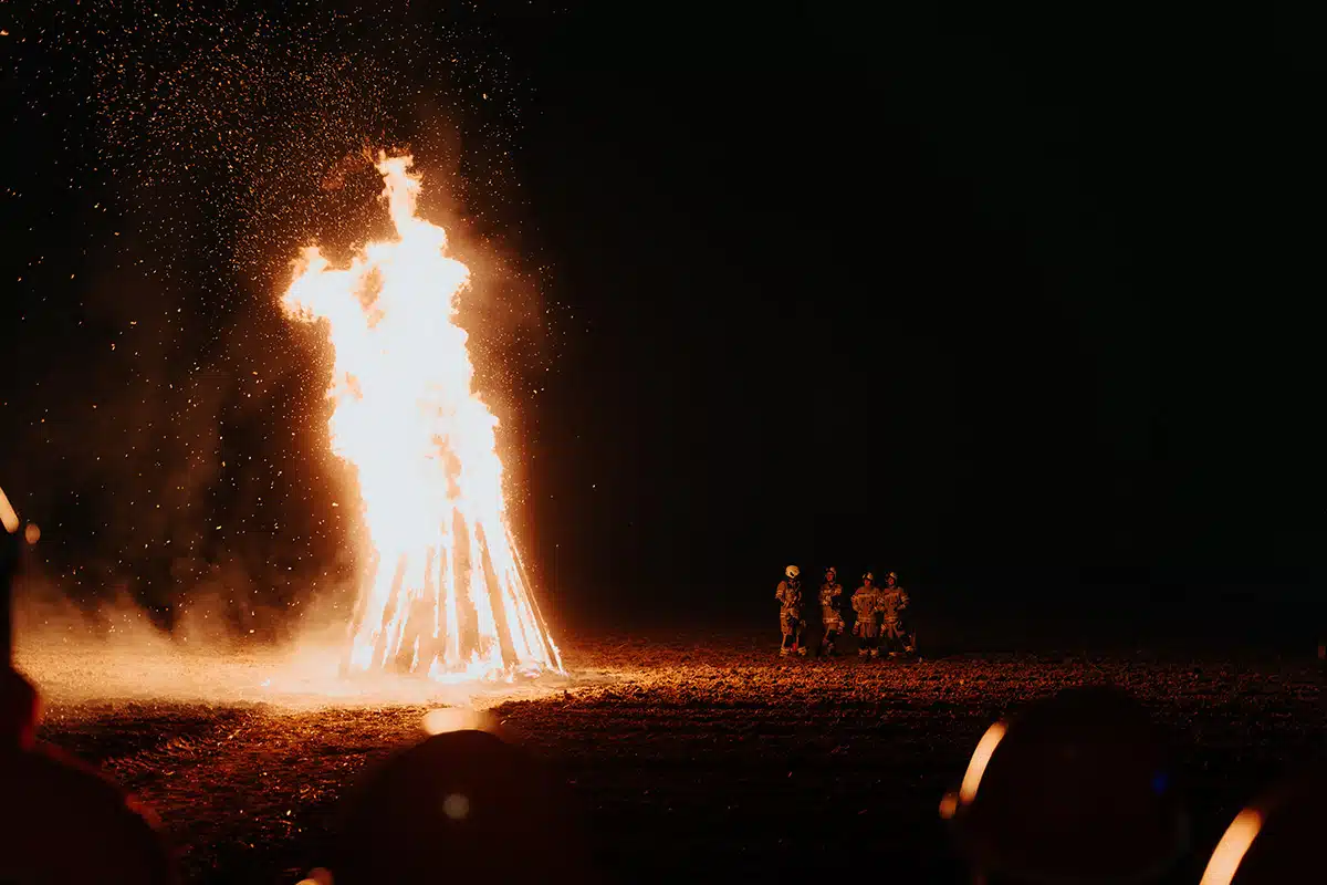 Das große Martinsfeuer brennt hell beim Martinszug Sankt Augustin Niederpleis 2024. Eine Gruppe Menschen schaut dabei zu.