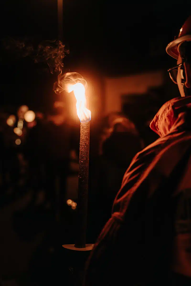 Ein Jugendfeuerwehrmann hält eine Fackel beim Martinszug Sankt Augustin Niederpleis 2024.
