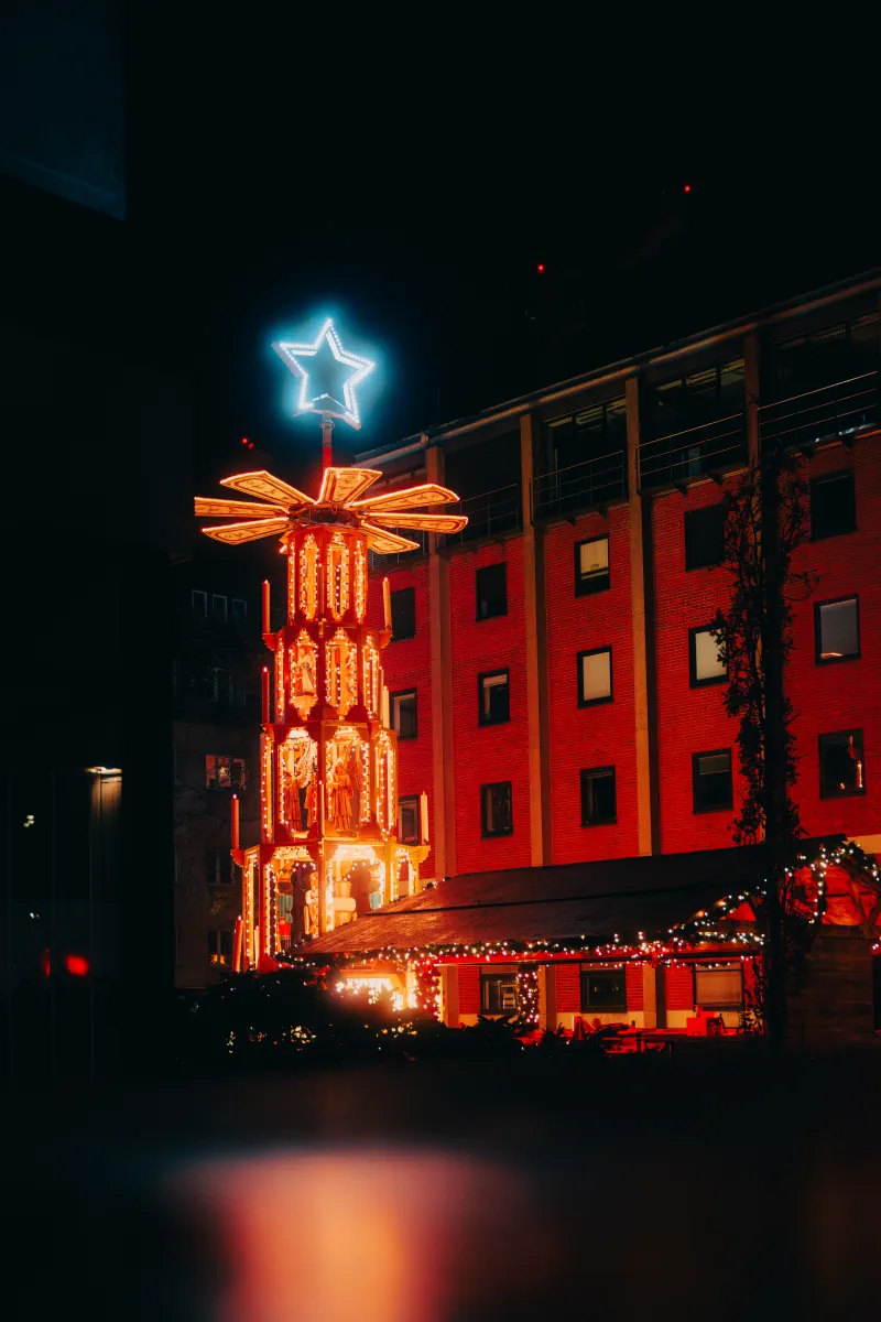 Eine große, beleuchtete Weihnachtspyramide im Weihnachtsdort auf dem Weihnachtsmarkt am Kölner Dom.