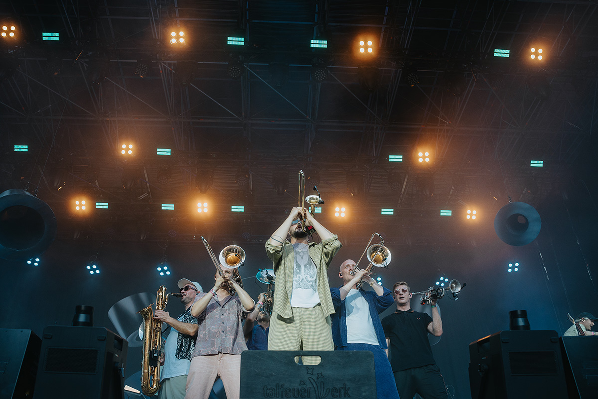 Querbeat live auf dem Festival Bonn 2025 – zentrale Formation der Bläsergruppe unter hellen Bühnenstrahlern, energetischer Moment mitten im Set. Fotografiert von Philipp Wildfeuer