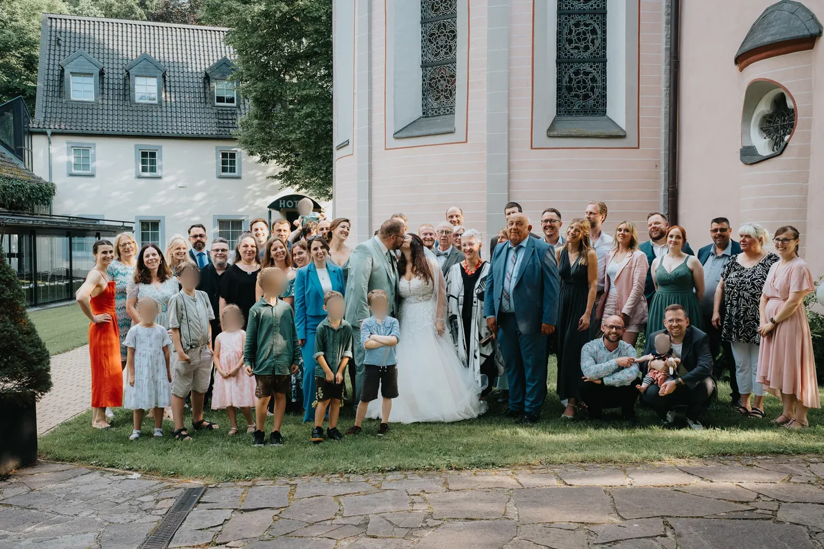Alle Hochzeitsgäste versammeln sich zu einem großen Gruppenfoto und winken in die Kamera; festgehalten vom Hochzeitsfotograf Neunkirchen‑Seelscheid.